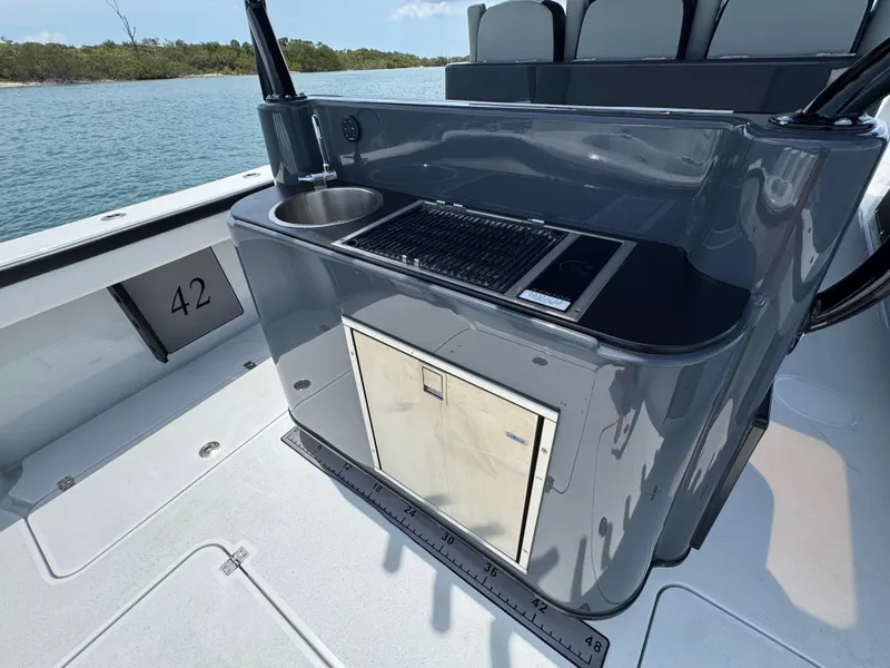 Slide: The Image of 2023 Yellowfin 42 boat with sleek outdoor kitchen and sink, set against a serene water backdrop. - 21