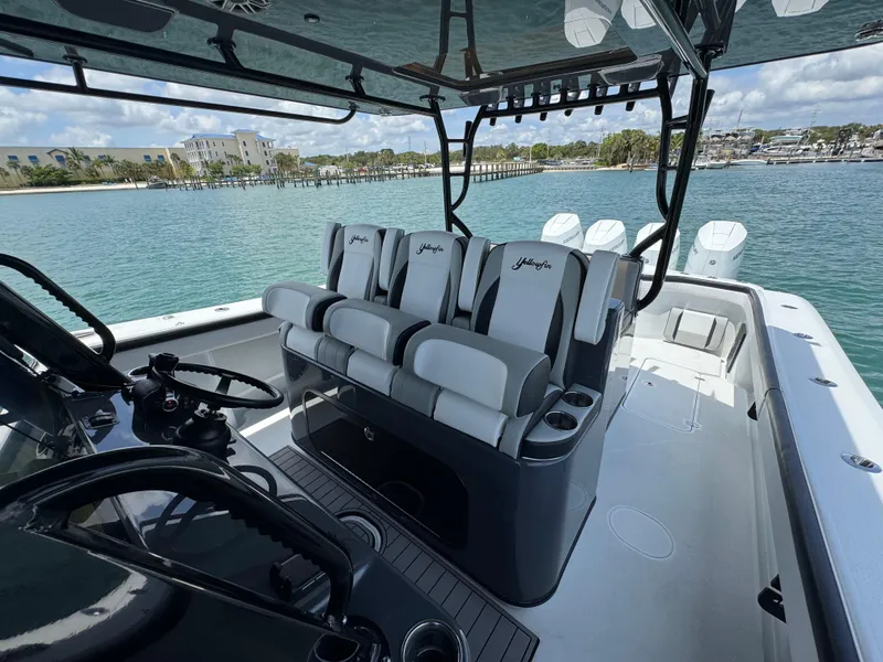 Slide: The Image of 2023 Yellowfin 42 boat interior with sleek seating and steering, docked by clear blue water. - 38
