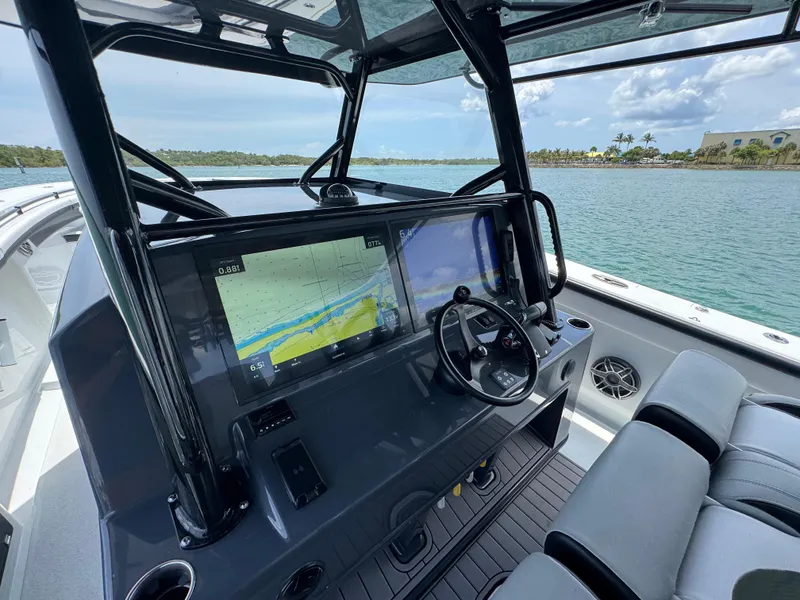 Slide: The Image of 2023 Yellowfin 42 boat cockpit with navigation screens and steering wheel, near scenic waterway. - 41