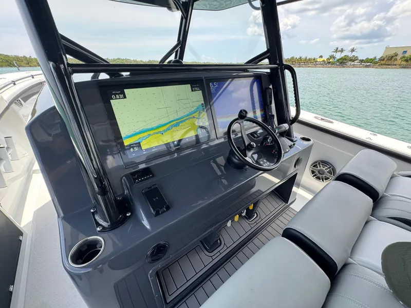 Slide: The Image of 2023 Yellowfin 42 boat dashboard with navigation screens and steering wheel, overlooking calm waters. - 42