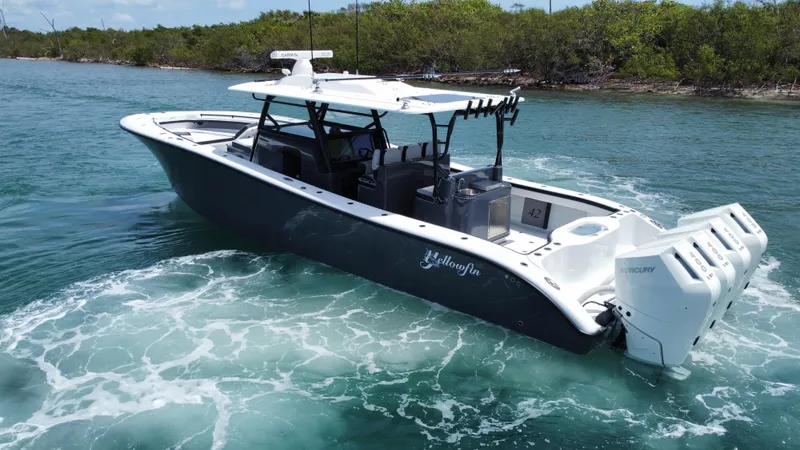 Slide: The Image of 2023 Yellowfin 42 boat cruising in clear blue water near a lush shoreline. - 7