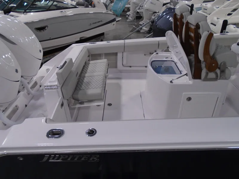 Slide: The Image of 2026 Jupiter 30 boat interior with seating and storage, showcased in a showroom. - 14