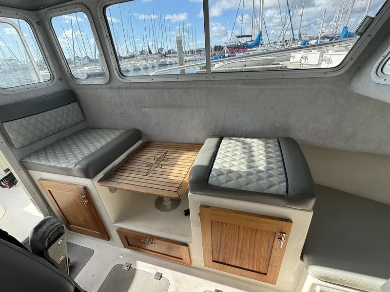 Slide: The Image of 2024 Defiance San Juan 220 interior with cushioned seating and wooden storage cabinets. - 15