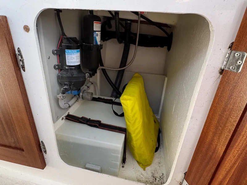 Slide: The Image of 2024 Defiance San Juan 220 storage compartment with pump and yellow life jacket. - 17