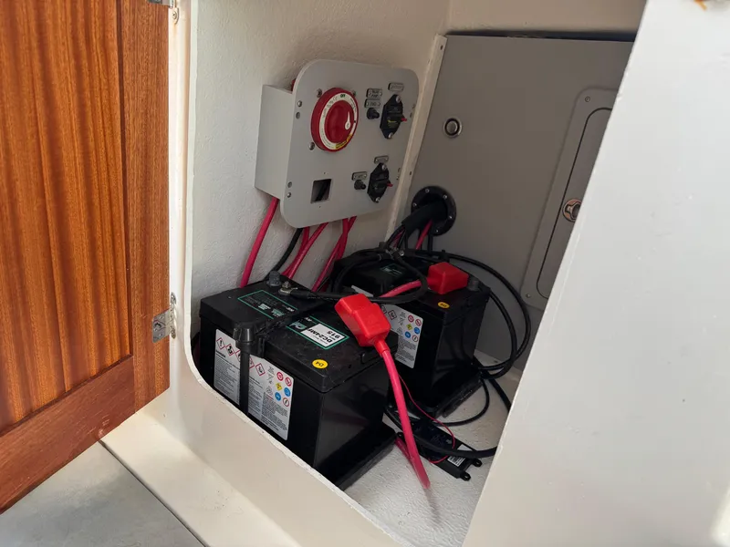 Slide: The Image of 2024 Defiance San Juan 220 boat battery compartment with dual batteries and wiring. - 18