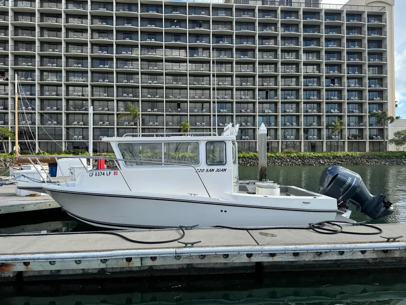 Slide: The Image of 2024 Defiance San Juan 220 boat docked in marina, with modern building backdrop. - 6