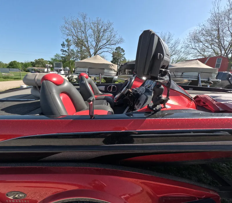 Slide: The Image of 2007 Ranger Z21 Comanche boat with red and black seats, parked outdoors. - 6