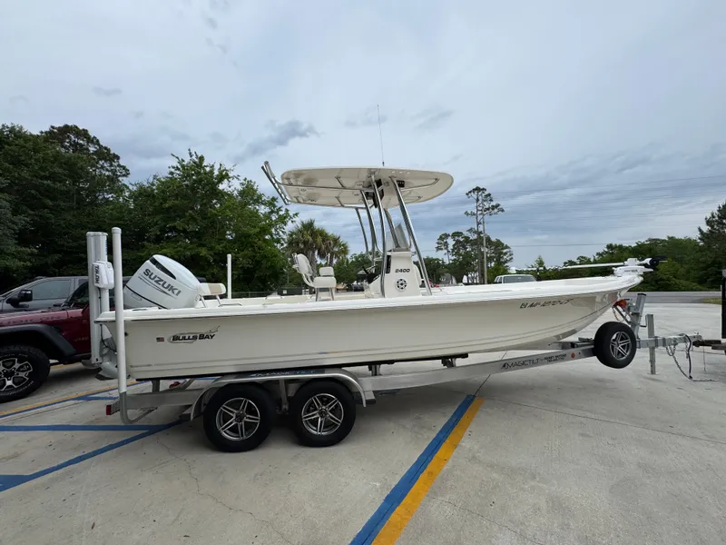 Slide: The Image of 2024 Bulls Bay 2400 boat on trailer with Suzuki outboard motor in parking lot. - 10