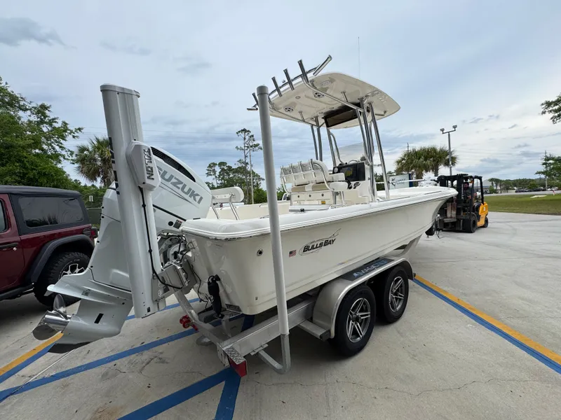Slide: The Image of 2024 Bulls Bay 2400 boat on trailer with Suzuki engine in parking lot. - 12