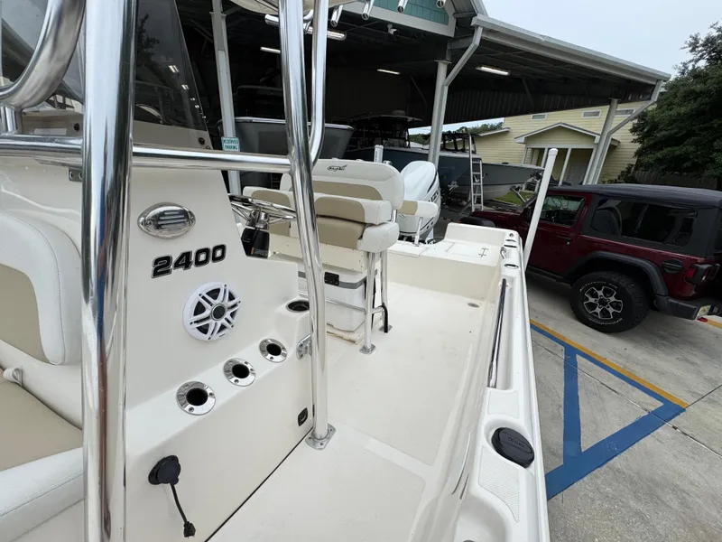 Slide: The Image of 2024 Bulls Bay 2400 boat interior with seating and equipment, parked near a vehicle. - 25