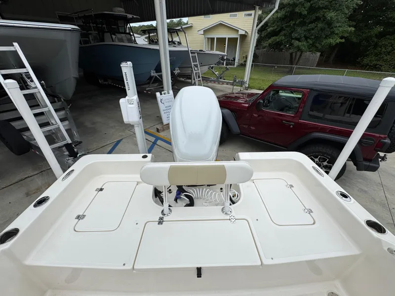 Slide: The Image of 2024 Bulls Bay 2400 boat interior with seating and storage, parked near a red vehicle. - 36