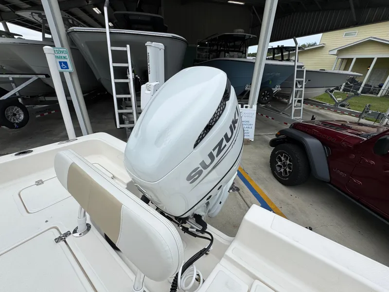 Slide: The Image of 2024 Bulls Bay 2400 boat with Suzuki outboard motor in a covered storage area. - 37