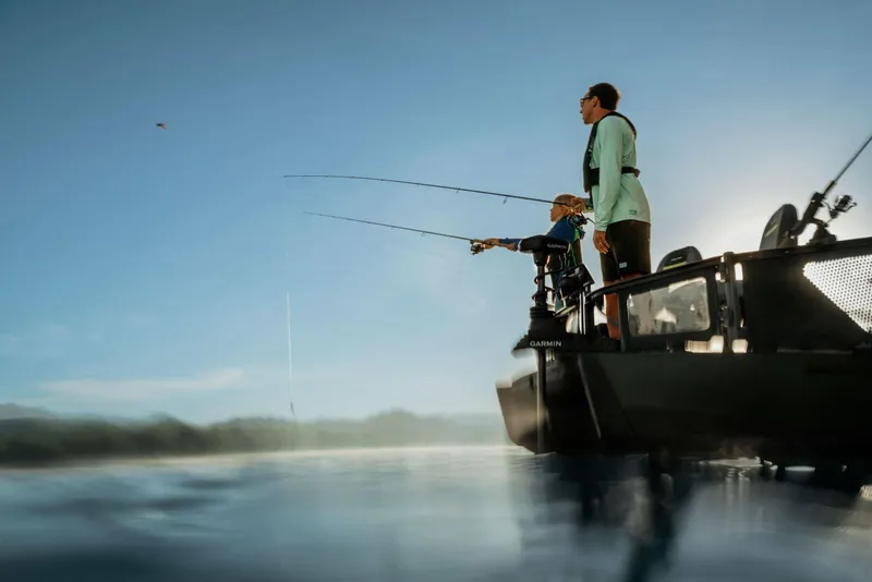 Slide: The Image of 2025 Sea-Doo Switch™ Fish 21 on water, two people fishing at sunrise. - 11