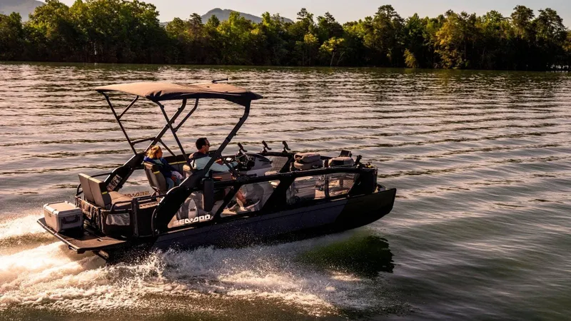Slide: The Image of 2025 Sea-Doo Switch™ Fish 21 boat cruising on a serene lake at sunset. - 9