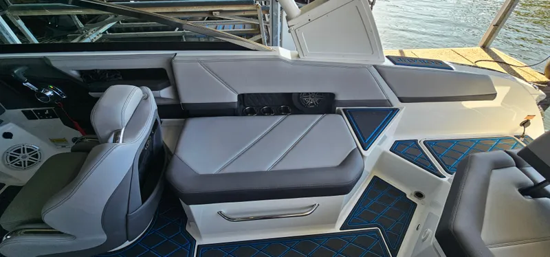 Slide: The Image of 2022 Cobalt R6 boat interior with gray seating and blue accents, docked by the water. - 11