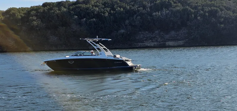 Slide: The Image of 2022 Cobalt R6 boat cruising on a scenic lake with forested shoreline. - 5