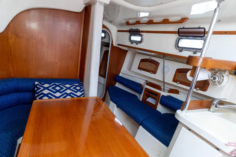 Slide: The Image of 2011 Hake Seaward 32 RK sailboat interior with wooden table, blue seating, and storage shelves. - 31