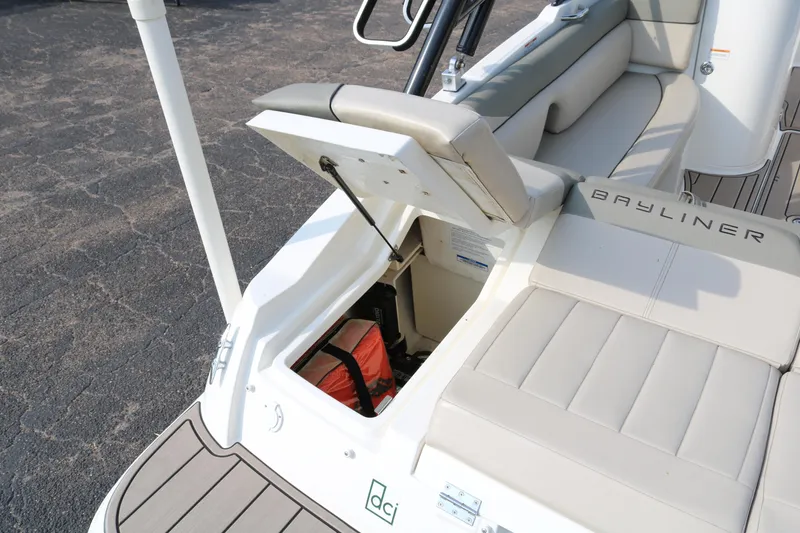 Slide: The Image of 2016 Bayliner 215 Deck Boat with open storage compartment and cushioned seating. - 12