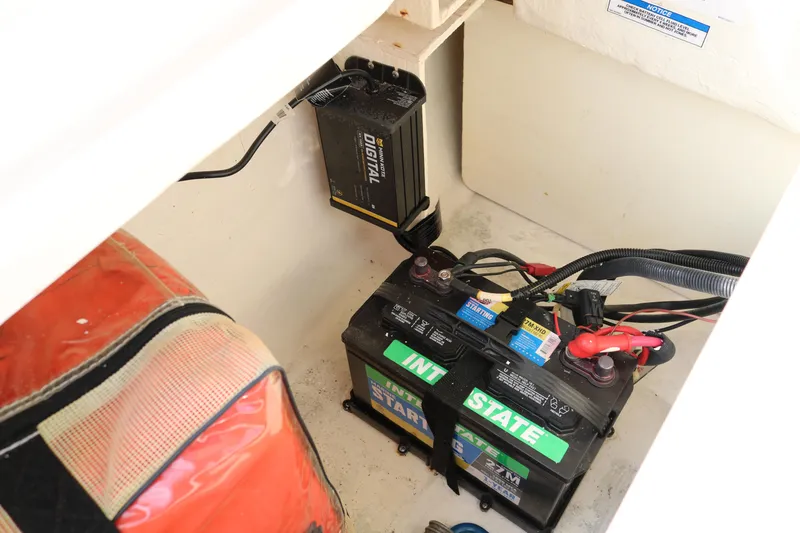 Slide: The Image of 2016 Bayliner 215 Deck Boat battery compartment with dual Interstate batteries and charger. - 13