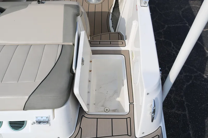 Slide: The Image of 2016 Bayliner 215 Deck Boat interior with open storage compartment and cushioned seating. - 16