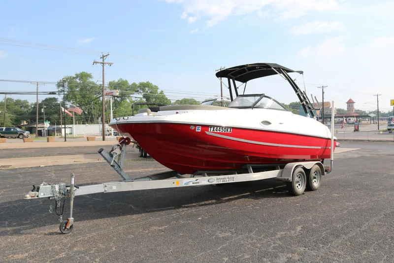 Slide: The Image of 2016 Bayliner 215 Deck Boat on trailer, red and white, parked outdoors. - 3