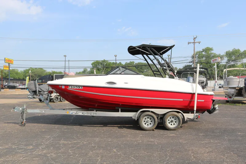 Slide: The Image of 2016 Bayliner 215 Deck Boat in red on a trailer, parked outdoors. - 4