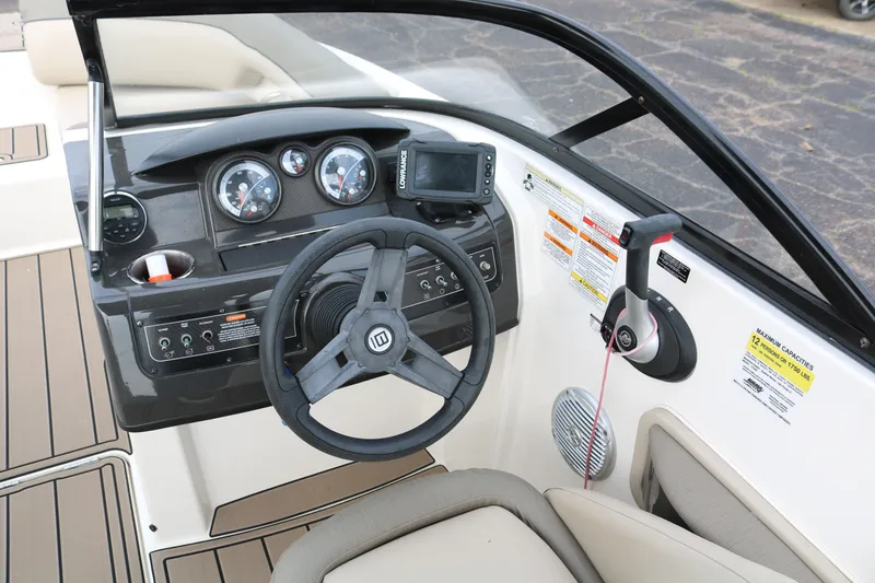 Slide: The Image of 2016 Bayliner 215 Deck Boat cockpit with steering wheel and control panel. - 42