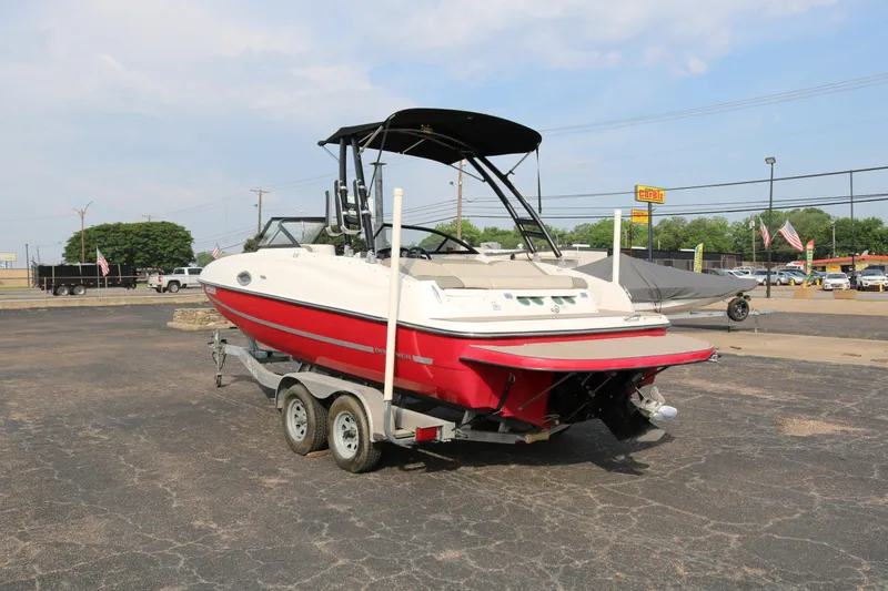 Slide: The Image of 2016 Bayliner 215 Deck Boat on trailer, red and white, parked outdoors. - 5