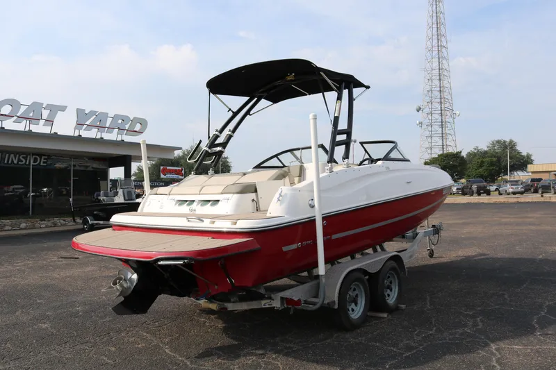 Slide: The Image of 2016 Bayliner 215 Deck Boat on trailer at boat yard, red and white exterior. - 7