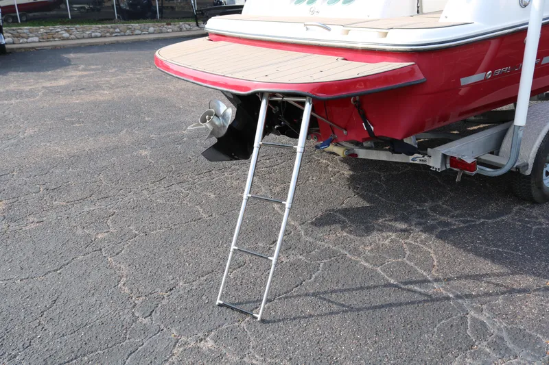 Slide: The Image of 2016 Bayliner 215 Deck Boat with ladder and trailer on pavement. - 9