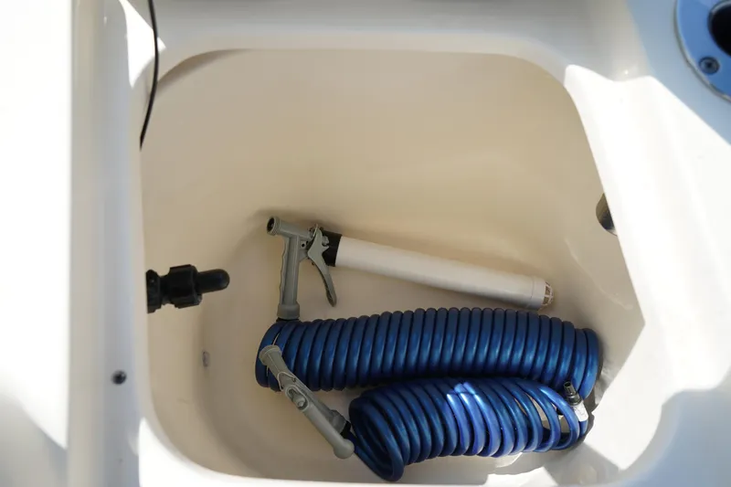 Slide: The Image of 2022 Scout 215 XSF boat compartment with coiled blue hose and nozzle. - 14