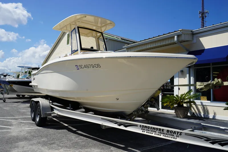 Slide: The Image of 2022 Scout 215 XSF boat on trailer outside dealership under blue sky. - 2