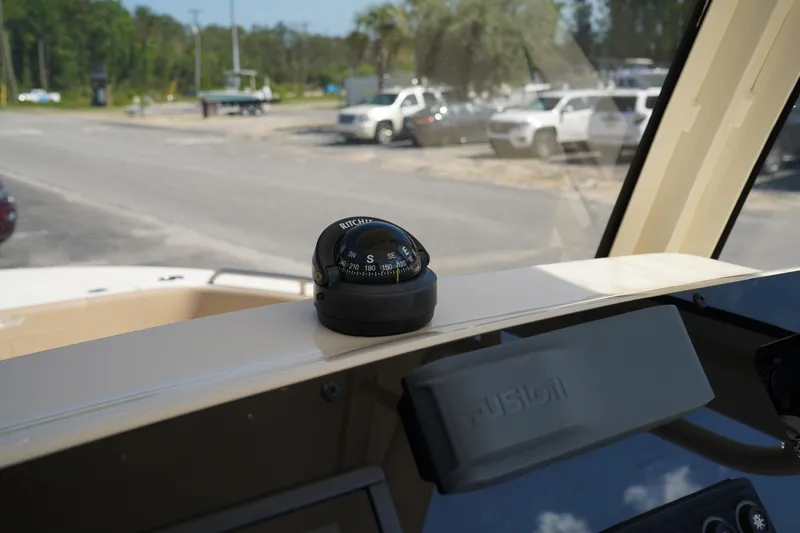 Slide: The Image of Compass on 2022 Scout 215 XSF boat dashboard, parked in a lot with vehicles. - 24