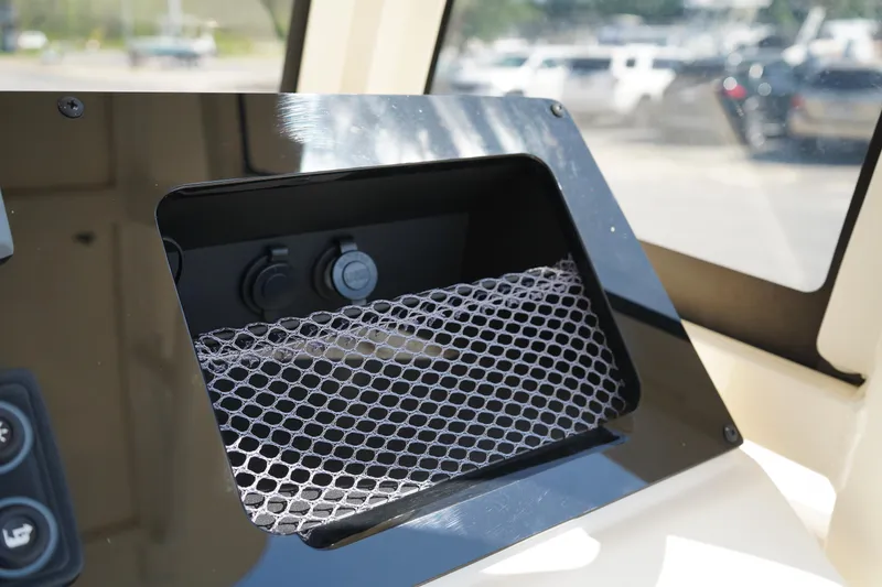 Slide: The Image of 2022 Scout 215 XSF boat dashboard with storage compartment and netting. - 28