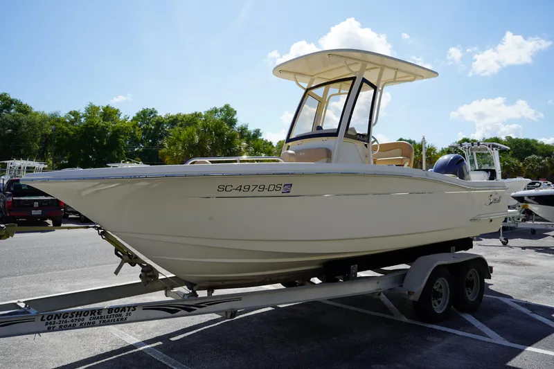 Slide: The Image of 2022 Scout 215 XSF boat on trailer, parked outdoors under a clear sky. - 3