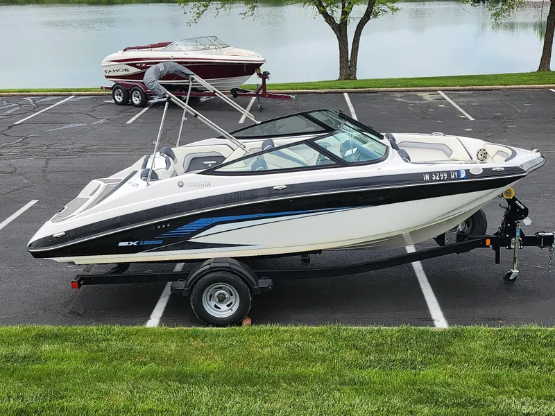 Slide: The Image of 2017 Yamaha Boats SX195 on trailer in parking lot near lake. - 0