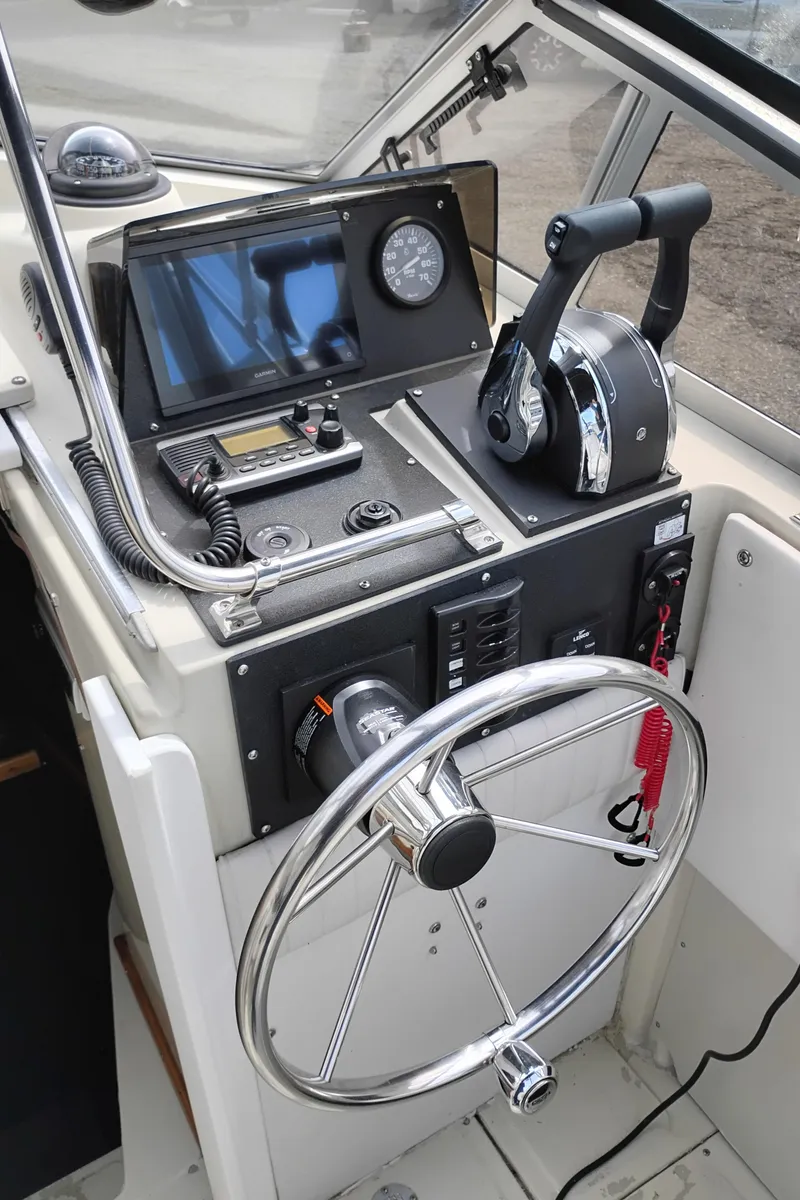 Slide: The Image of 1989 Boston Whaler 22 Renegade Cabin helm with steering wheel and control panel. - 10