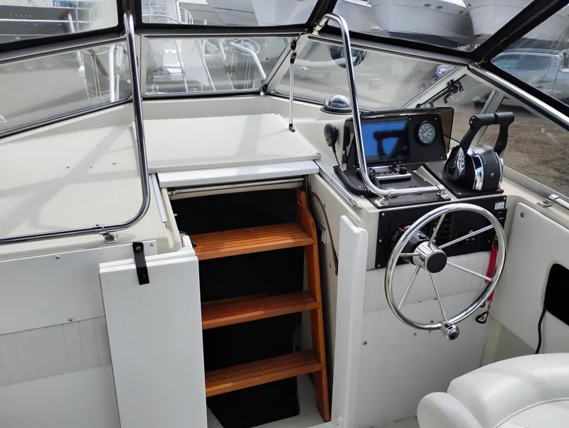 Slide: The Image of 1989 Boston Whaler 22 Renegade Cabin interior with steering wheel and wooden steps. - 16