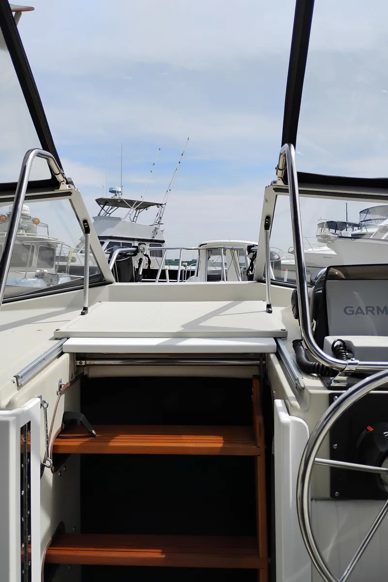 Slide: The Image of 1989 Boston Whaler 22 Renegade Cabin interior with open hatch and visible steering wheel. - 28