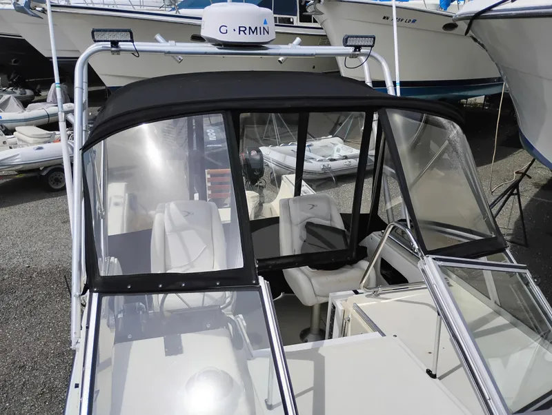 Slide: The Image of 1989 Boston Whaler 22 Renegade Cabin with Garmin radar, black canopy, and white seating. - 29