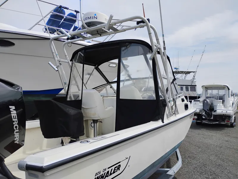 Slide: The Image of 1989 Boston Whaler 22 Renegade Cabin boat with Mercury engine, docked outdoors. - 3