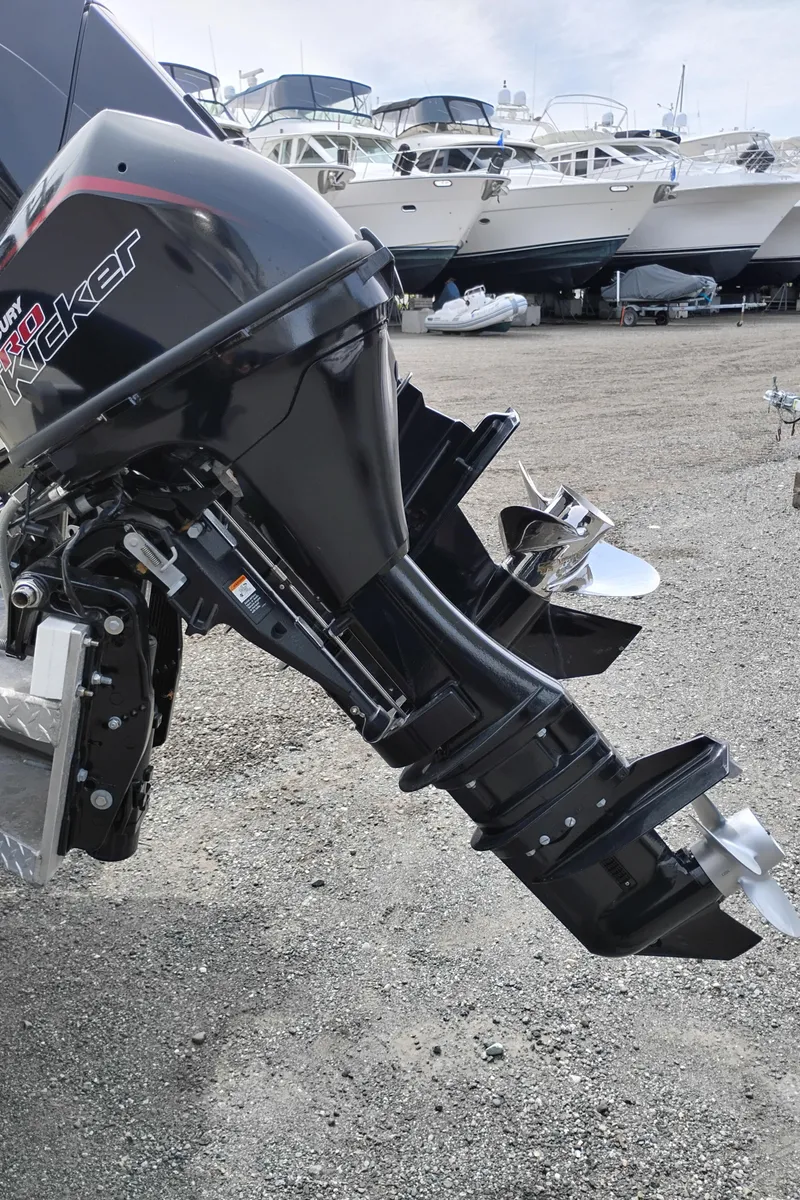 Slide: The Image of 1989 Boston Whaler 22 Renegade Cabin with outboard motor, parked on gravel near other boats. - 6