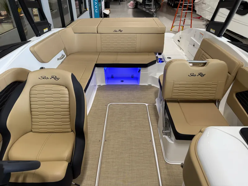 Slide: The Image of 2025 Sea Ray SPX230 boat interior with tan seating and blue LED lighting. - 13