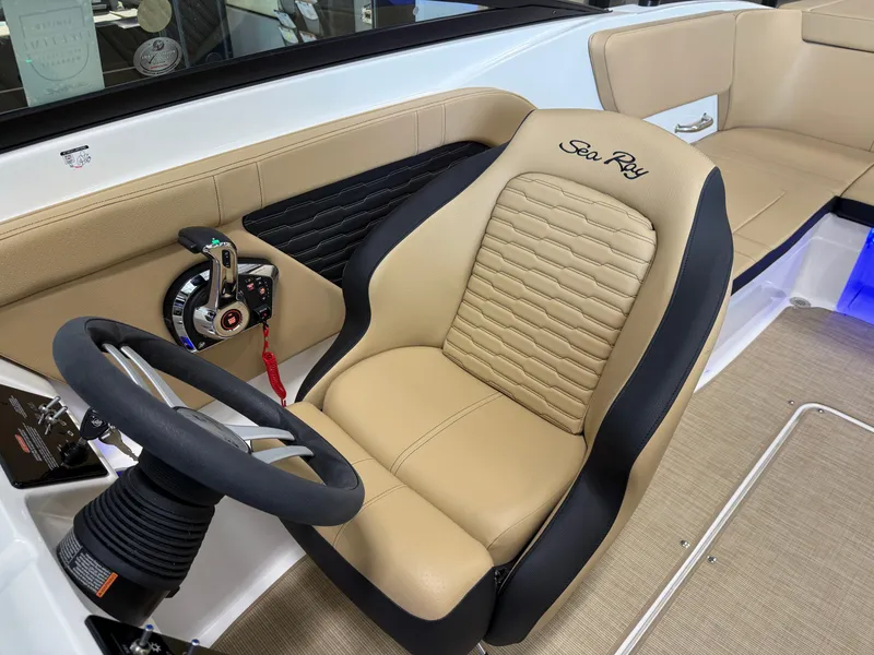Slide: The Image of 2025 Sea Ray SPX230 boat interior with beige seating and steering wheel. - 14