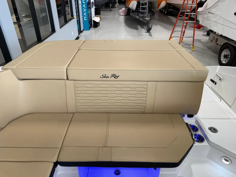 Slide: The Image of 2025 Sea Ray SPX230 boat interior with beige seating and logo. - 18