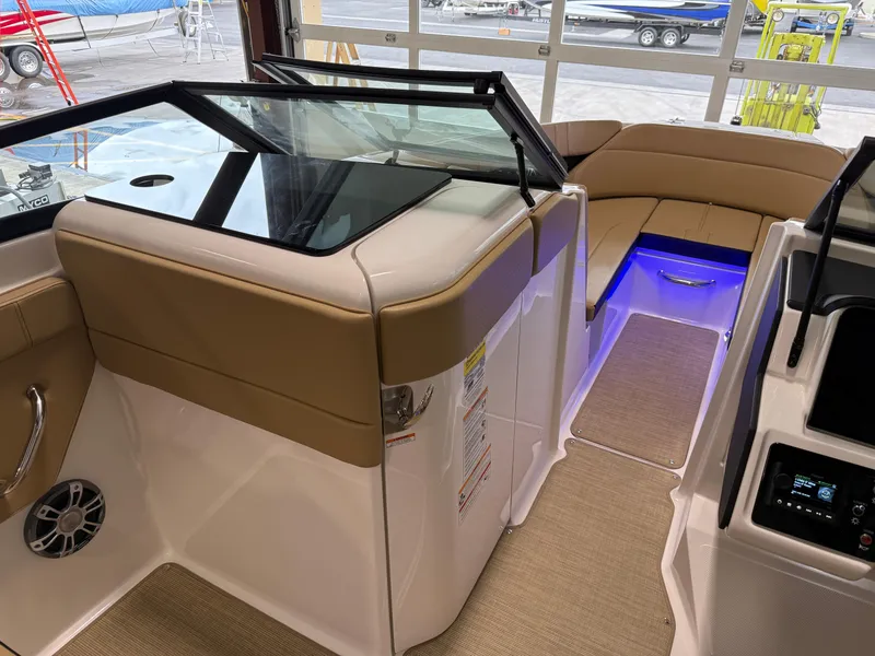 Slide: The Image of 2025 Sea Ray SPX230 boat interior with tan seating and blue LED lighting. - 35
