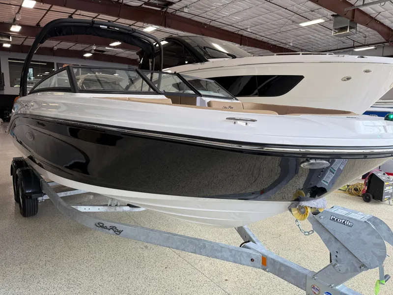 Slide: The Image of 2025 Sea Ray SPX230 boat on trailer in showroom, sleek black and white design. - 8
