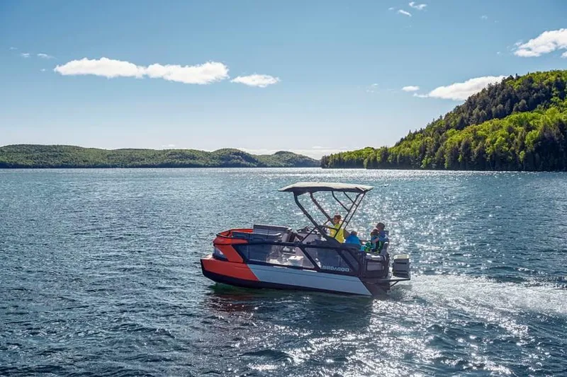 Slide: The Image of 2024 Sea-Doo Switch® Cruise 18 on scenic lake with lush green hills. - 5