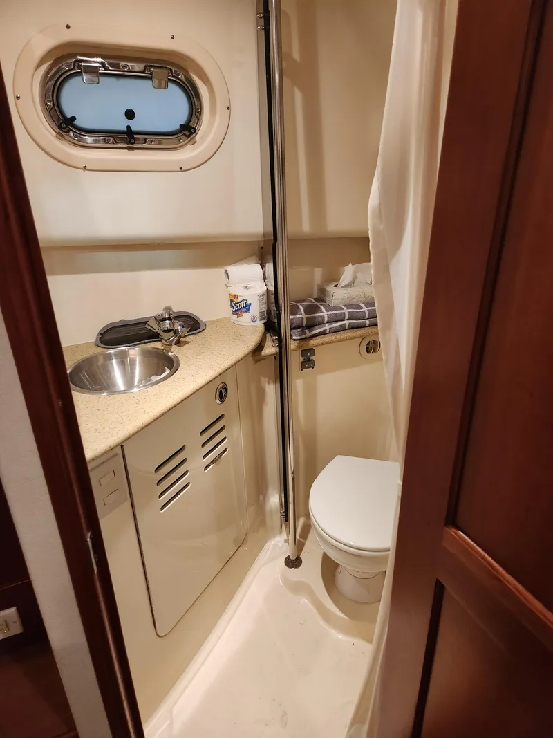 Slide: The Image of 2010 Mainship Pilot 31 boat bathroom with sink, toilet, and porthole window. - 15