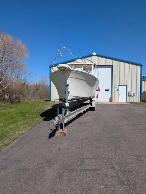 Slide: The Image of 2010 Mainship Pilot 31 boat on trailer outside a storage building under clear blue sky. - 20